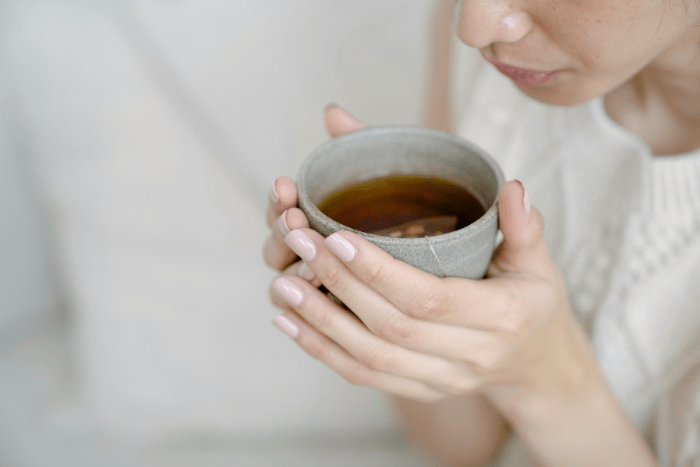 Una ragazza con una tazza fumante si rilassa in un momento di quiete, sostenendo il corpo e la postura durante i malanni di stagione.