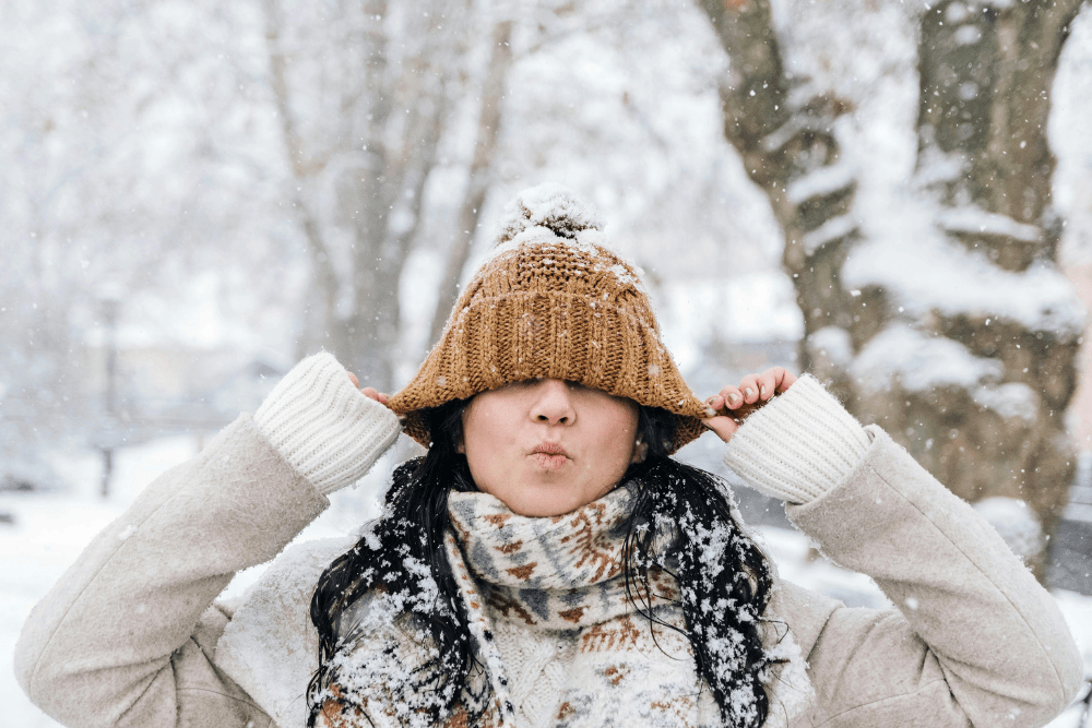 Una ragazza in mezzo alla neve mantiene una postura aperta e armoniosa, simbolo di equilibrio e benessere durante i malanni di stagione.