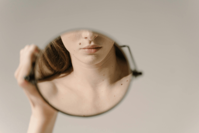 Una persona si osserva allo specchio con postura rilassata e sguardo attento, simbolo del movimento consapevole e dell’ascolto del corpo come pratica quotidiana di osservazione e consapevolezza.